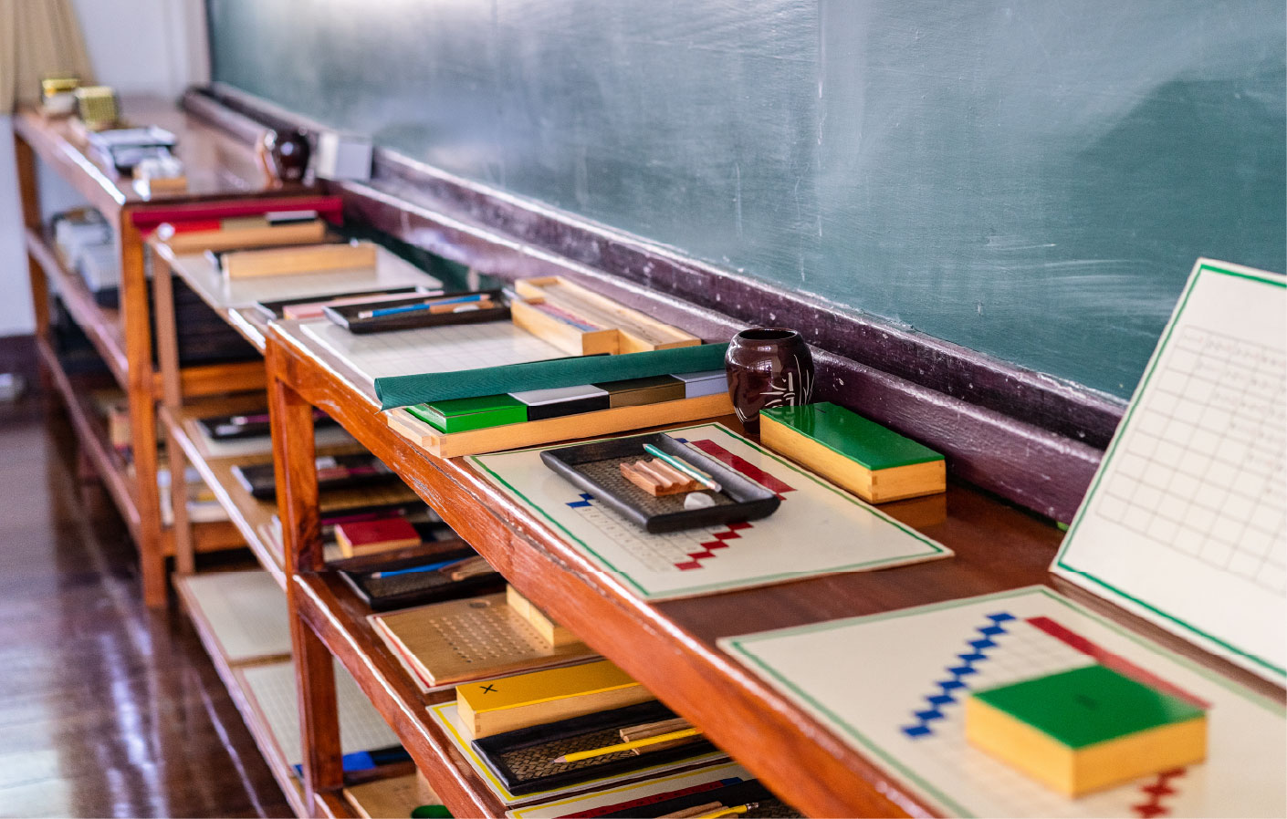 Shelves displaying various tools and materials for learning, set underneath a blackboard. 